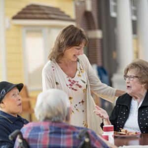 Woman talking with nursing home residents while eating